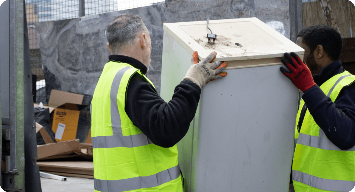 team loading fridge into rubbish removal truck